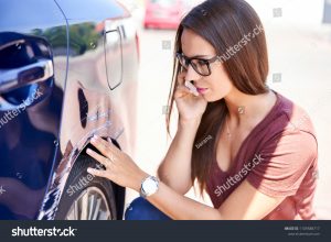 stock-photo-young-woman-making-phone-call-to-insurance-agent-while-inspecting-scratched-car-1109588717